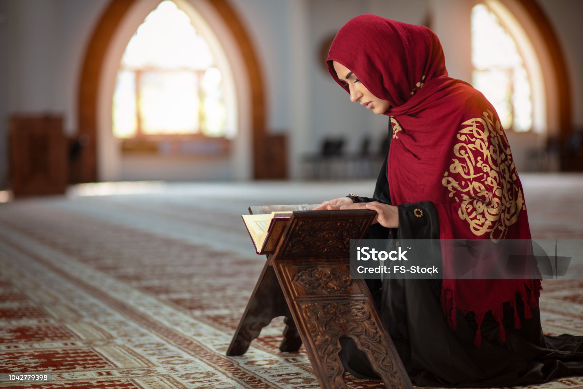 Muslim woman in white clothes falling on knees and offering up prayer in mosque